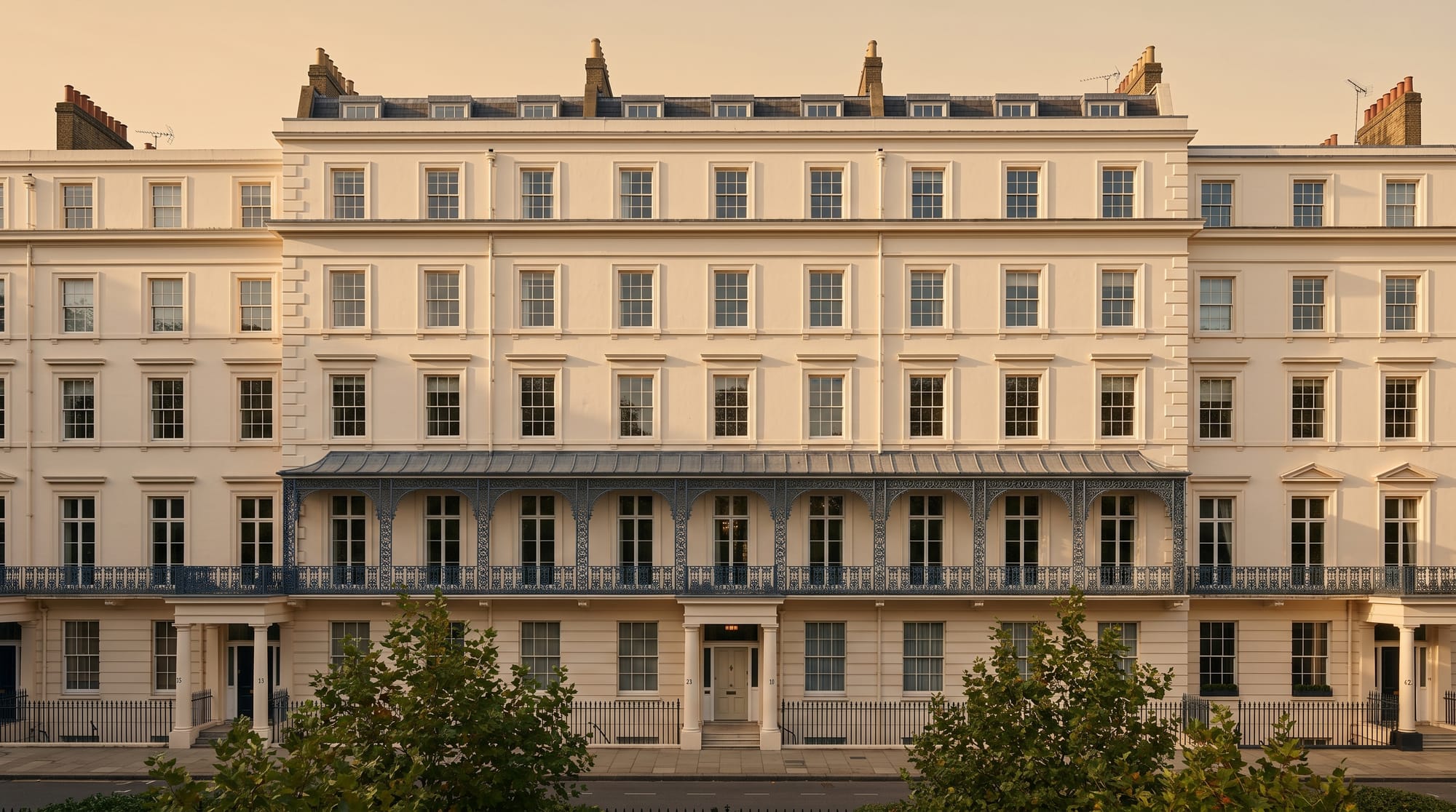 The southern terrace of Eaton Square seen from the communal gardens — Cubitt stucco facade, sash fenestration, iron balcony railings.